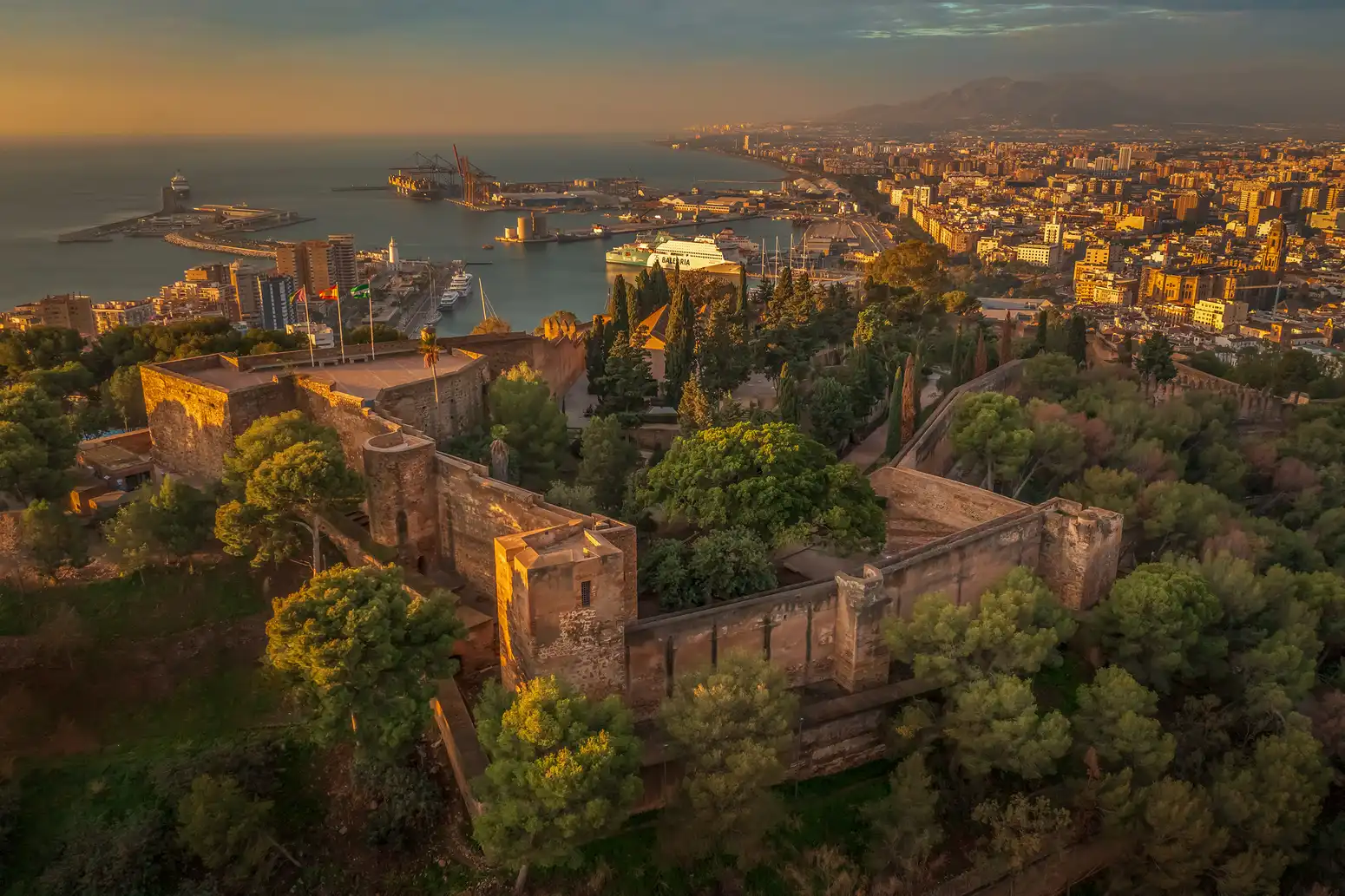 Murallas de la Alcazaba de Málaga al atardecer, con el puerto al fondo